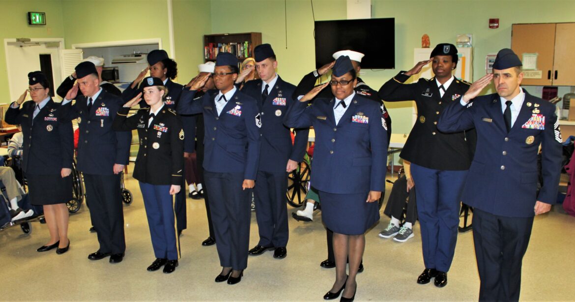 CMSgt Benjamin Higginbotham, far right, performs an Honor Salute for veterans at an assisted living facility along with other members of the military.
