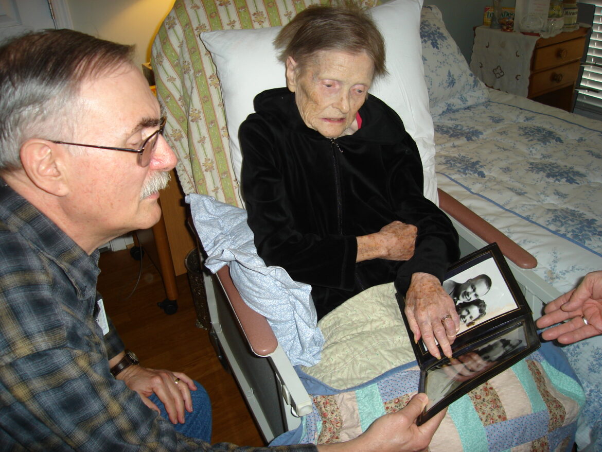 Volunteer Russ Stewart visits with a patient who shares family photos with him. Volunteers like Russ are vital members of the clinical team, providing patients a safe space to share.