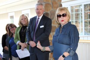 Hospice of the Chesapeake’s Gift Processing Specialist Lisa Young, Director of Advancement Chris Wilson and President and CEO Mike Brady listen in as Calvert County Councilmember Catherine Grasso shares her family’s many connections to the not-for-profit’s hospice care at the Burnett Center for Hope & Healing ribbon-cutting.